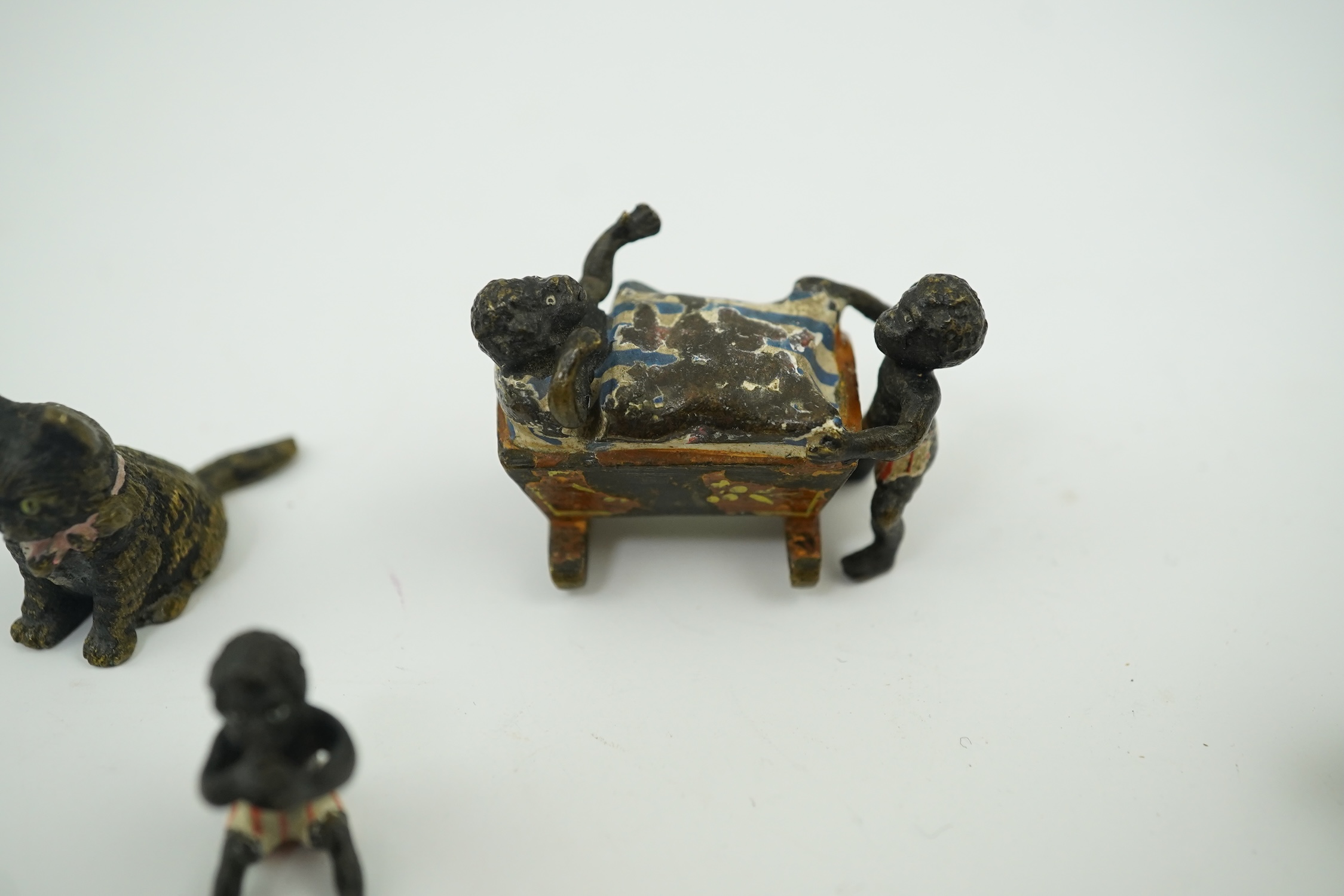 Four novelty miniature cold painted bronzes; black boy with cradle, black baby, cat and pig and a similar articulated arm skeleton stickpin,7cm long. Condition - some chipping to paint